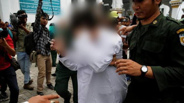 Syariah policemen hold an Indonesian man after public caning . Caning is also a punishment in Aceh for gambling, drinking alcohol, women who wear tight clothes and men who skip Friday prayers. (Beawiharta / REUTERS)