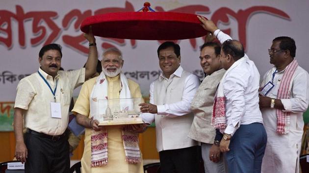 Prime Minister Narendra Modi receives a memento from Assam chief minister Sarbananda Sonowal as BJP workers hold an Assamese Japi, a traditional headgear, in Guwahati on Friday. (AP) Prime Minister Narendra Modi receives a memento from Assam chief minister Sarbananda Sonowal as BJP workers hold an Assamese Japi, a traditional headgear, in Guwahati on Friday. (AP)