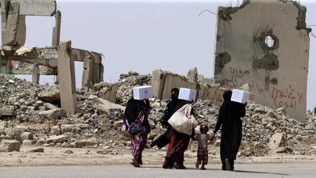 Iraqi women walk past destroyed buildings south of Mosul on May 26, 2017, as government forces continue their offensive to retake the city of Mosul from Islamic State (IS) group fighters.(AFP Photo)