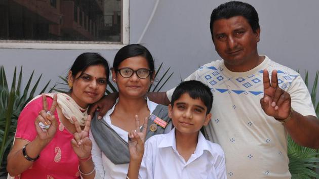 Vaishali, who ranked third in Jalandhar district with 96.46% marks, with her parents. (HT PHOTO)