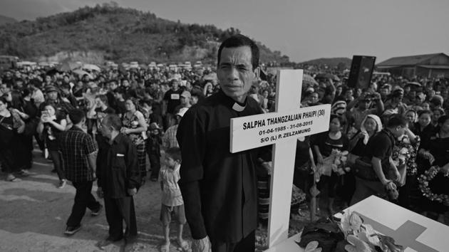 A pastor holds a wooden cross at the graveyard. On May 10 this year, an agreement was reached between the tribal leaders and the Manipur government in the form of a memorandum of understanding (MoU) – on condition that the dead should be buried by May 25. (Ravi Choudhary/HT PHOTO)