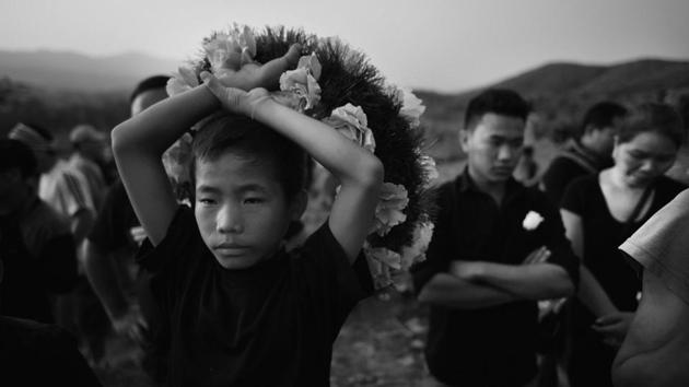A young boy seen carrying a wreath at the grave. The issue of non-burial troubled the centr. An elaborate political theatre was on show – featuring angry tribals, politicians, the armed forces, militants and the inter-tribe conflicts. (Ravi Choudhary/HT PHOTO)