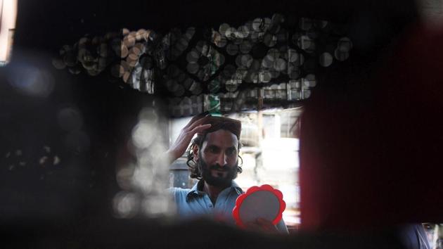 A Pakistani Muslim tries on a prayer cap at a roadside stall in Karachi. (Asif Hassan/AFP) A Pakistani Muslim tries on a prayer cap at a roadside stall in Karachi. (Asif Hassan/AFP)
