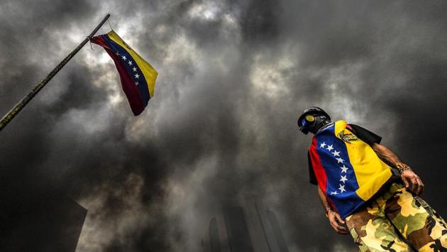An anti-government demonstrator stands next to a national flag during an opposition protest blocking the Francisco Fajardo highway in Caracas. Demonstrations that got underway in late March have claimed the lives of 58 people, as opposition leaders seek to ramp up pressure on Venezuela's leftist president, whose already-low popularity has cratered amid ongoing shortages of food and medicines, among other economic woes. (LUIS ROBAYO / AFP)