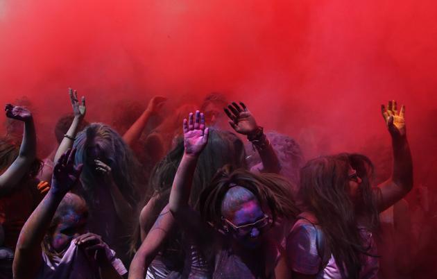 Revelers dance after throwing colored powders in the air. (Manu Fernandez / AP)