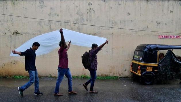 Men use a plastic sheet to cover from rain as they walk along a road in Kochi. (Sivaram V/Reuters) Men use a plastic sheet to cover from rain as they walk along a road in Kochi. (Sivaram V/Reuters)