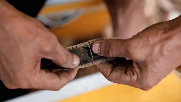 A worker re-connects a broken film strip before a wedding party. But earnings have fallen steadily in the mobile cinema business as the younger middle class flocks to air-conditioned movie theatres that offer reclining chairs, or even beds, alongside fast food and soft drinks. (REUTERS)