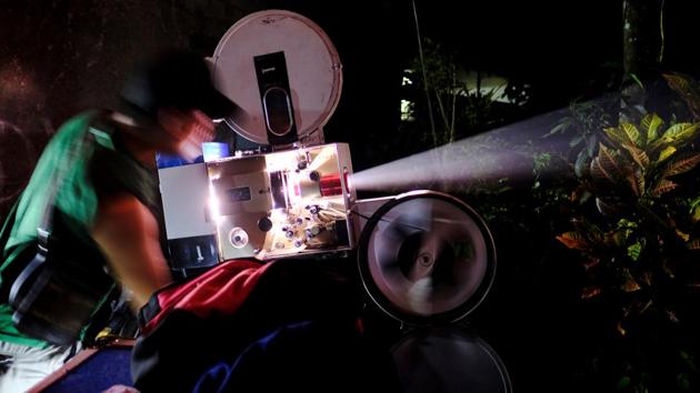 An operator adjusts a film projector during a party in Bogor. At the venue, usually an open field or outside the home of a customer holding a party or celebration, people gather to watch as Kamaluddin sets up his equipment. (REUTERS)