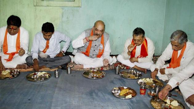BJP president Amit Shah and other leaders have a meal at a tribal's house in Devaliya village in Gujarat on Wednesday.(PTI) BJP president Amit Shah and other leaders have a meal at a tribal's house in Devaliya village in Gujarat on Wednesday.(PTI)
