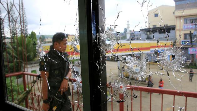A policeman stands on guard behind a window full of bullet holes in Marawi city, Philippines. (Reuters Photo) A policeman stands on guard behind a window full of bullet holes in Marawi city, Philippines. (Reuters Photo)