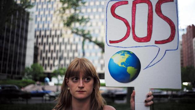 A woman displays a placard during a demonstration in New York on June 1, 2017, to protest US President Donald Trump's decision to pull out of the 195-nation Paris climate accord deal. US President Donald Trump earlier announced America is "getting out" of a deal he said imposed "draconian" burdens that would cost the US millions of jobs and billions in cold hard cash. / AFP PHOTO / Jewel SAMAD (AFP) A woman displays a placard during a demonstration in New York on June 1, 2017, to protest US President Donald Trump's decision to pull out of the 195-nation Paris climate accord deal. US President Donald Trump earlier announced America is "getting out" of a deal he said imposed "draconian" burdens that would cost the US millions of jobs and billions in cold hard cash. / AFP PHOTO / Jewel SAMAD (AFP)