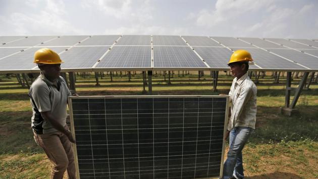 Workers carry a damaged photovoltaic panel inside a solar power plant in Gujarat, India. (File Photo)(Reuters)