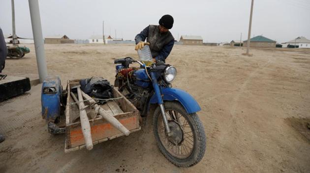 A fisherman refuels his motorcycle in the village of Karateren.   Some villages are once again within walking distance from the lake while the water has become much less salty, allowing a greater diversity of fish to thrive. (Shamil Zhumatov / REUTERS) 
