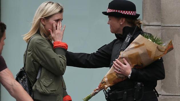 A woman reacts after asking a police officer to lay flowers near London Bridge in London on June 4, 2017, as a tribute to the victims of the June 3 terror attack.(AFP Photo)