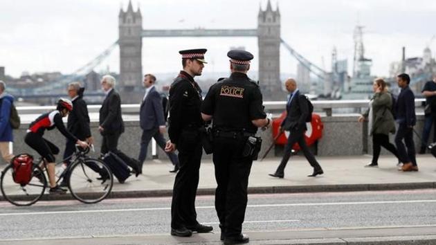 Commuters travel past City of London police officers standing on London Bridge after is was reopened following an attack which left 7 people dead and dozens injured in central London.(Reuters Photo)