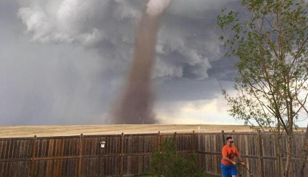 A Canadian man calmly mowing the lawn while a tornado rages behind him. Photo Credit: Cecilia Wessels (Facebook)