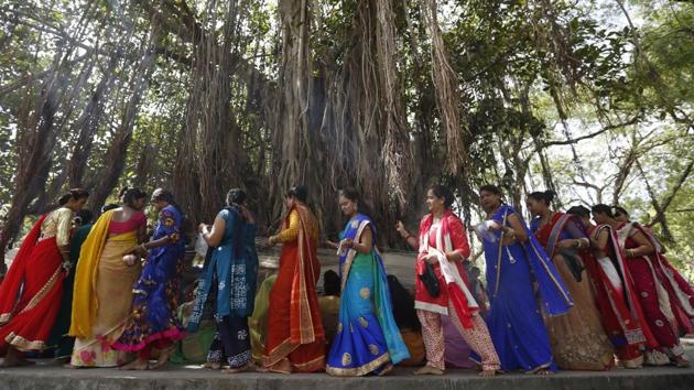 Women in groups move together to offer prayers to the banyan tree. Ganga water is poured and threads of red or yellow colour are tied around the tree chanting prayers. (Ajit Solanki / AP)