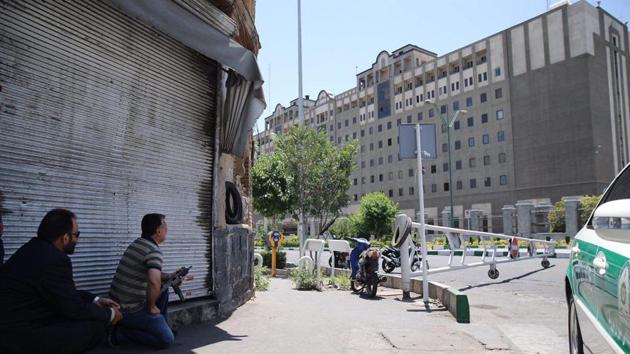 An undercover Iranian policeman (L) holds a weapon outside the Iranian parliament during an attack on the complex. (OMID VAHABZADEH/AFP)