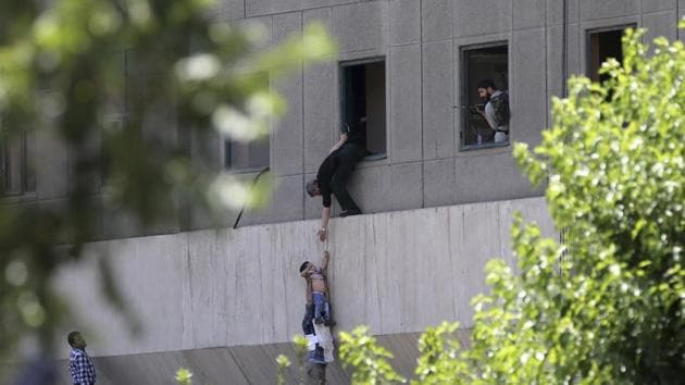A man hands a child to a security guard after an assault at the parliament in Tehran. (OMID VAHABZADEH/AP)
