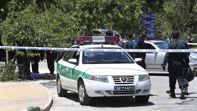 The body of a suspected terrorist, at background left, lies on the ground as police control the scene at the shrine of Ayatollah Khomeini. AP Photo/Ebrahim Noroozi (Ebrahim Noroozi/AP)
