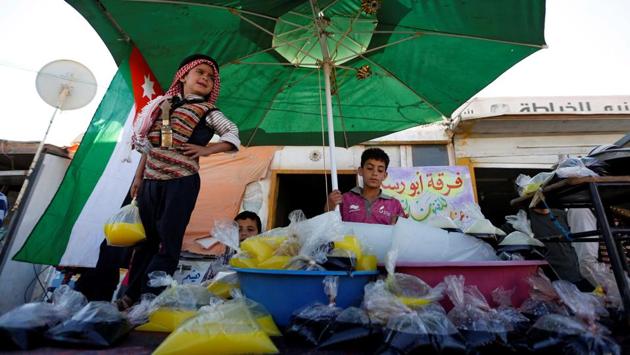 Members of the Syrian refugee troupe Abu Rustom, sell traditional juices at the Al-Zaatari refugee camp near the border with Syria. (REUTERS) Members of the Syrian refugee troupe Abu Rustom, sell traditional juices at the Al-Zaatari refugee camp near the border with Syria. (REUTERS)