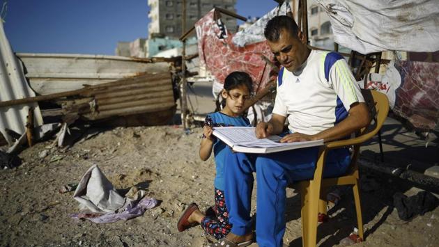 A Palestinian man reads a copy of the Quran, to a young girl at Al-Shatee refugee camp in Gaza City. (AFP) A Palestinian man reads a copy of the Quran, to a young girl at Al-Shatee refugee camp in Gaza City. (AFP)