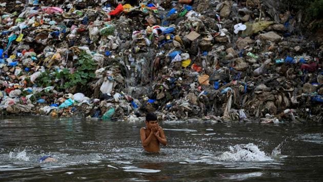A child swims in a polluted river with a mound of trash in the background in Rawalpindi, Pakistan. (Caren Firouz/REUTERS)