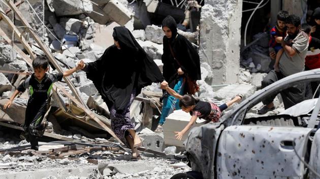 Civilians displaced by fighting between the Iraqi forces and Islamic State militants walk past destroyed houses. (Erik De Castro / Reuters)