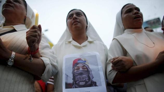 A nun wearing a photograph of protester Neomar Lander marches with others to the site where he died in Caracas, Venezuela. (AP) 