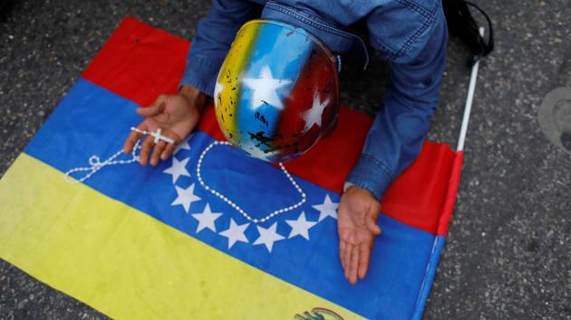 Seen above, a man prays over a national flag during a protest march.  (REUTERS) 