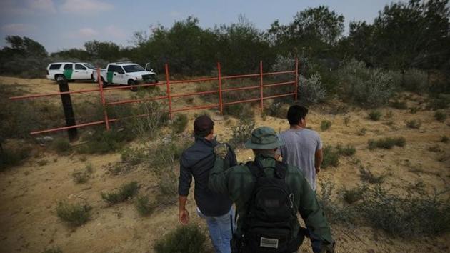 A U.S. border patrol agent escorts men being detained after entering the United States by crossing the Rio Grande river from Mexico. (REUTERS) A U.S. border patrol agent escorts men being detained after entering the United States by crossing the Rio Grande river from Mexico. (REUTERS)