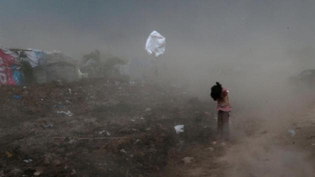 A girl protects herself from garbage and dust, raised by a gust of wind, in a slum in Islamabad, Pakistan. (Caren Firouz / REUTERS)