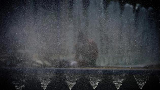 A boy wets himself with water from a street fountain in Sevilla. (CRISTINA QUICLER / AFP)