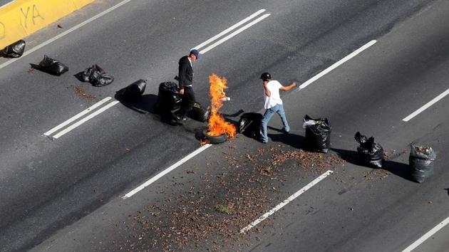 A man sets a tire on fire during protests . (Ivan Alvarado / REUTERS)