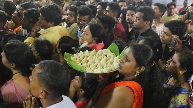 A woman holding a plate of sweets, called ‘modak’, in a crowd of devotees at Lalbaugcha Raja pandal. (Bhushan Koyande/HT PHOTO)