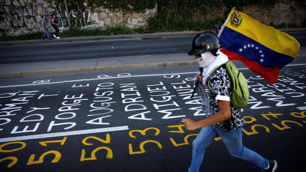 A demonstrator carries a Venezuelan flag as he runs next to a list . Anti-government protesters want new elections and have called for President Nicolas Maduro’s resignation. (Ivan Alvarado / REUTERS)