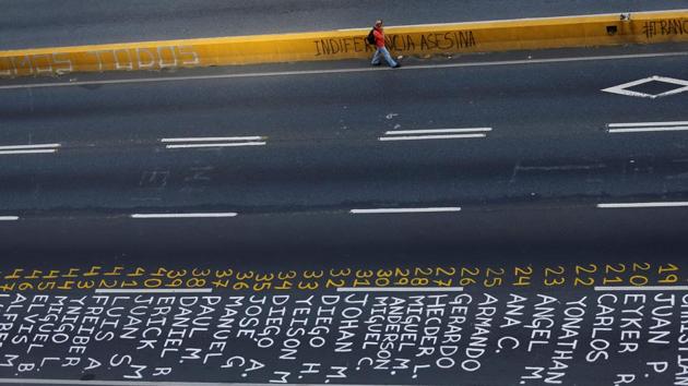 A pedestrian walks past a list of the victims of the violence. (Ivan Alvarado / REUTERS)