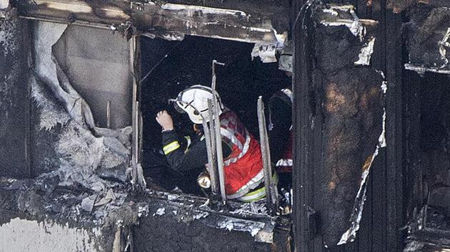 A firefighter checks damage after a fire engulfed the 24-storey Grenfell Tower, in west London.(AP Photo)