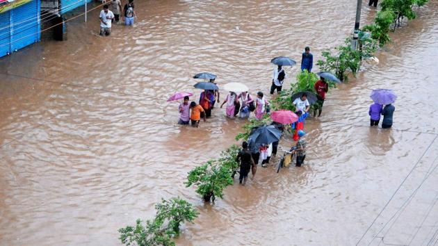 People make their way through a flooded street after heavy rainfall . (PTI) People make their way through a flooded street after heavy rainfall . (PTI)