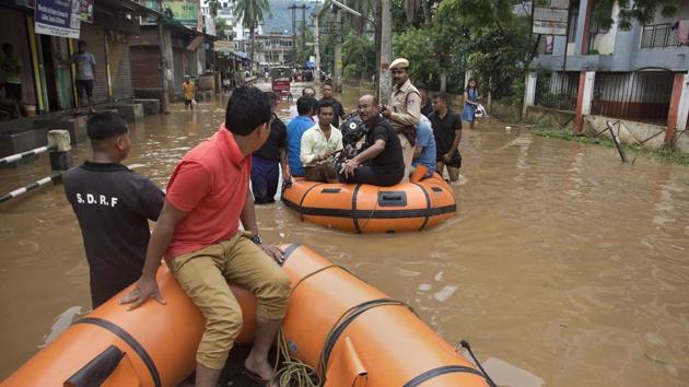 State Disaster Response Force personnel arrive on rafts to rescue flood affected people through a road waterlogged in Tuesday's monsoon rain in Guwahati, Assam, India, June 14, 2017.(AP)