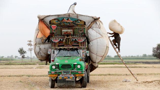 Workers load straw onto a decorated truck in Pakistan. (Caren Firouz/REUTERS)