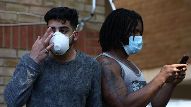 People wear masks near a tower block severely damaged by a serious fire. (Neil Hall / REUTERS)