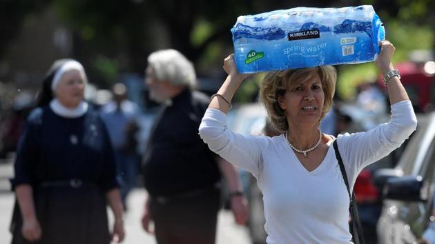 A woman carries water near a tower block severely damaged by a serious fire. (Toby Melville / REUTERS)