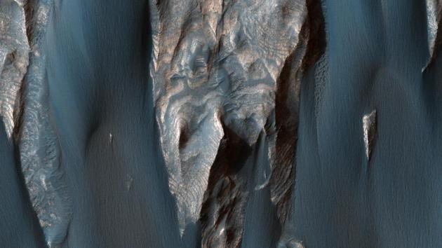 Windblown Sand in Ganges Chasma: Dark, windblown sand covers intricate sedimentary rock layers in this image captured by NASA’s (MRO) from Ganges Chasma, a canyon in the Valles Marineris system. In a paper published recently in Earth and Planetary Science Letters, scientists in the ARES Division at NASA’s Johnson Space Center in Houston report that early Mars may have been quite similar to early Earth, and so these environments might have been habitable.