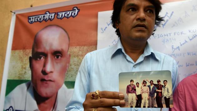 Friends of Kulbhushan Jadhav hold a photograph of them with Jadhav in the neighbourhood where he grew up in Mumbai, on May 18, 2017.(AFP Photo)