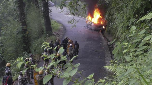 Security personnel watch from a distance as a vehicle torched by suspected protestors after a raid at GJM chief Bimal Gurung’s office, goes up in flames in Darjeeling, West Bengal. (AP) Security personnel watch from a distance as a vehicle torched by suspected protestors after a raid at GJM chief Bimal Gurung’s office, goes up in flames in Darjeeling, West Bengal. (AP)