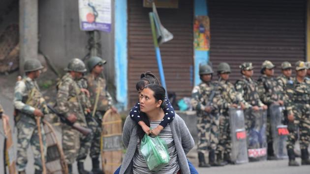 A woman carries her child as paramilitary personnel stand guard on June 16, 2017. Schools, ATMs and markets also remained closed. (Diptendu Dutta/AFP) A woman carries her child as paramilitary personnel stand guard on June 16, 2017. Schools, ATMs and markets also remained closed. (Diptendu Dutta/AFP)