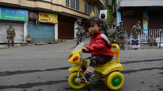 A child rides her tricycle as paramilitary personnel stand guard in the background in Darjeeling, on June 16, 2017. (Diptendu Dutta/AFP) A child rides her tricycle as paramilitary personnel stand guard in the background in Darjeeling, on June 16, 2017. (Diptendu Dutta/AFP)