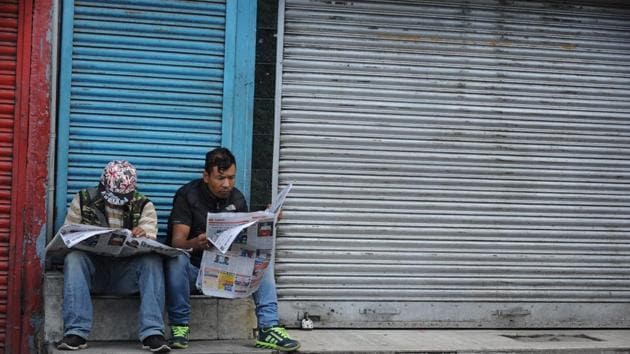 Resident sit outside a shuttered shop reading newspapers with normal life at a pause and an indefinite strike in place. (Diptendu Dutta/AFP) Resident sit outside a shuttered shop reading newspapers with normal life at a pause and an indefinite strike in place. (Diptendu Dutta/AFP)