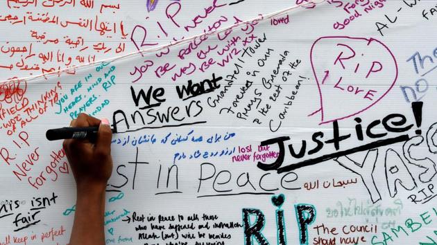 A woman writes on a message wall near the scene of the fire which destroyed the Grenfell Tower block, in north Kensington, West London, Britain. (REUTERS) A woman writes on a message wall near the scene of the fire which destroyed the Grenfell Tower block, in north Kensington, West London, Britain. (REUTERS)
